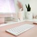Low angle shot of desk with pink pc screen, keyboard and mouse. glasses case, plant and light desk décor in back right of desk