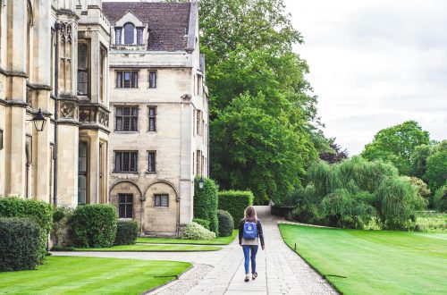 centre: girl walking down a path with backpack. left: university building. right: grass and bushes