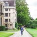 centre: girl walking down a path with backpack. left: university building. right: grass and bushes